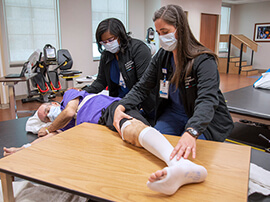 Two therapists lending support to patient with outstretched leg