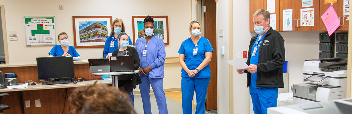 Nurses at a nurses station having a stand-up meeting.
