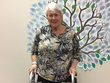 Barbara Wall stands with her walker in Northshore Hospital.