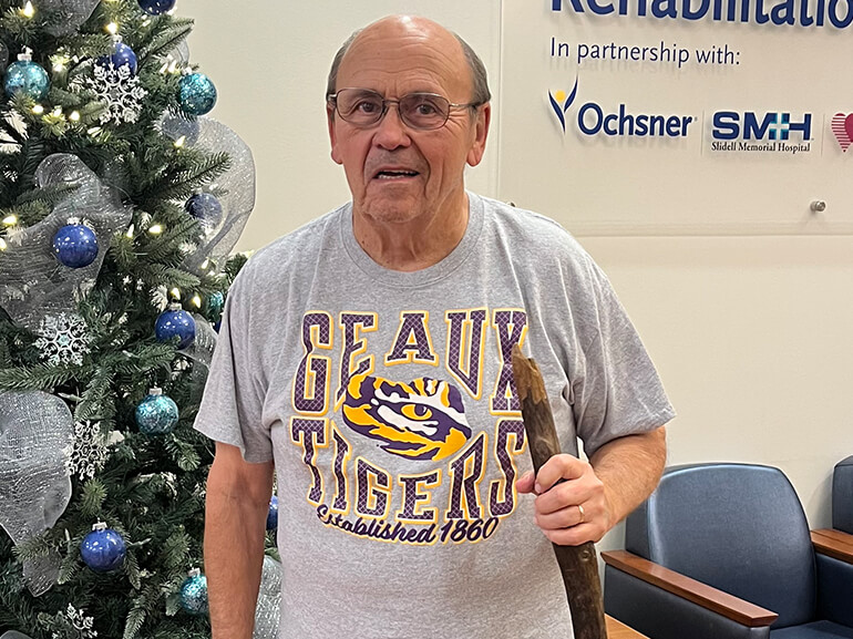 Joe Arroyo stands with a walking stick in the lobby of Northshore Rehabilitation Hospital