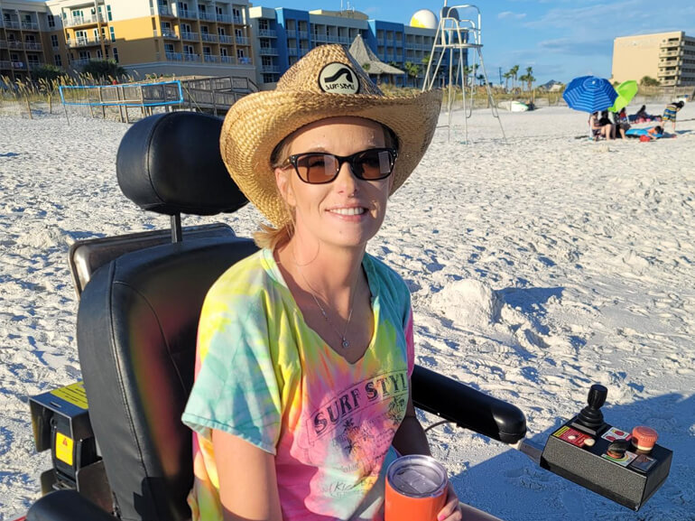 Miranda Gill smiles at the beach in her sand wheelchair.